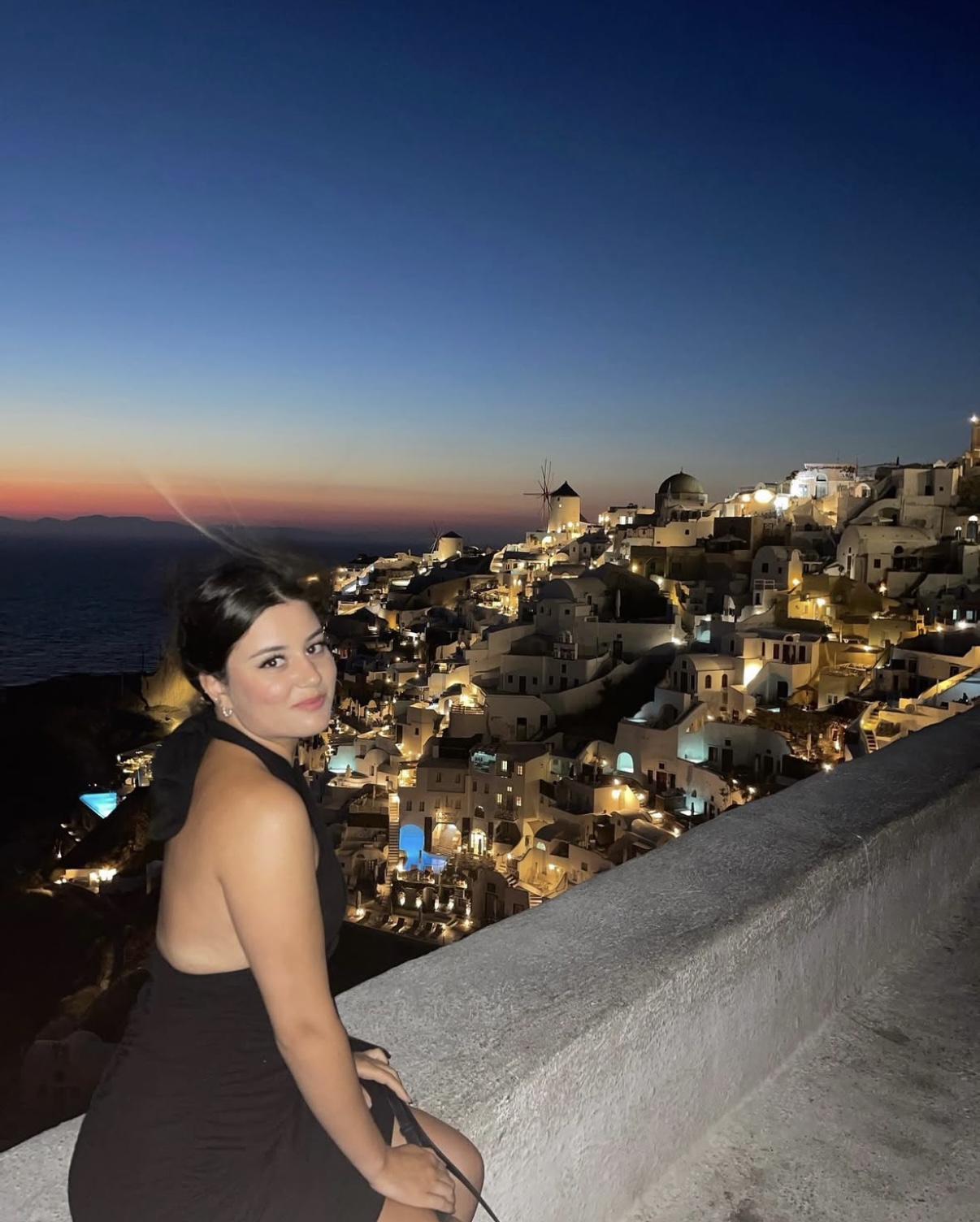Screenshot Vue nocturne sur Oia illuminée avec silhouette au premier plan